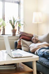 Laptop on table by man resting at home