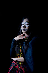 Portrait of woman wearing mask against black background