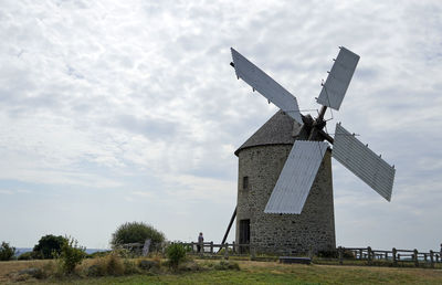 Traditional windmill on field against sky