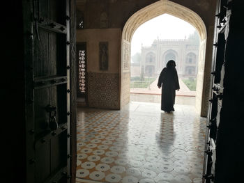 Rear view of man walking in corridor of building