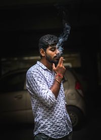 Young man smoking cigarette at night