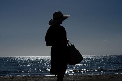 Silhouette man standing at beach against sky