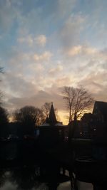 Silhouette building and trees against sky at sunset