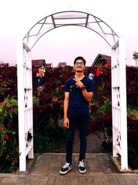 Portrait of young man standing against plants