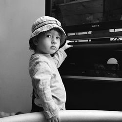 Portrait of cute girl standing by television set at home