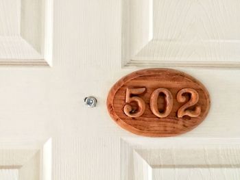 Close-up of wooden house address number on white door