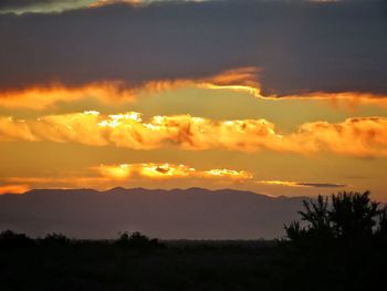 Scenic view of silhouette mountains against orange sky