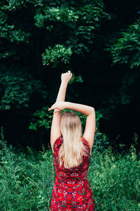 Midsection of woman standing by tree on field