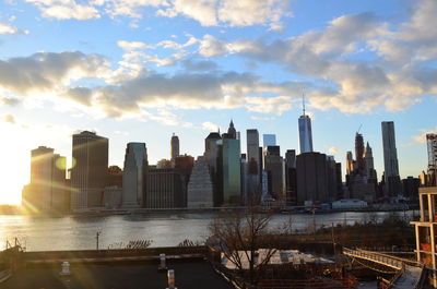 City at waterfront against cloudy sky