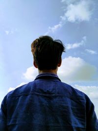 Rear view of teenage girl standing against sky