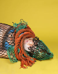 Dead woman trapped in rope and fishing net against yellow background