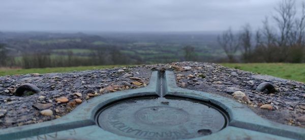 Close-up of rusty wheel on field against sky