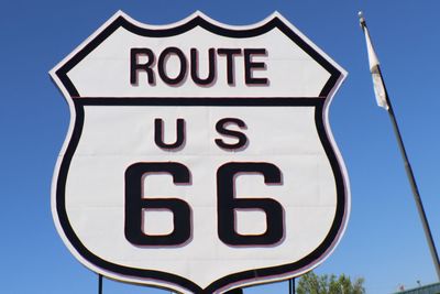 Low angle view of road sign against clear blue sky