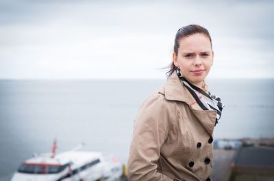 Portrait of young woman standing against sea