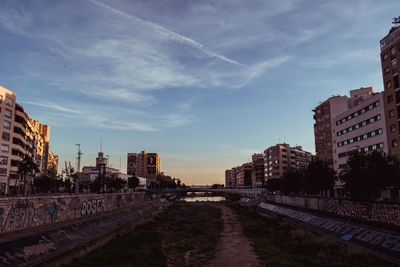 Road amidst buildings in city against sky at sunset in malaga river