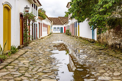 Cobblestone street with colorful colonial houses and reflections in the puddles in city of paraty