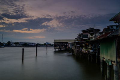 Scenic view of river by buildings against sky during sunset
