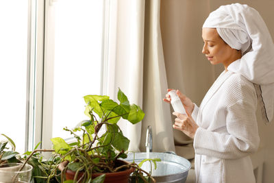 Side view of young woman using mobile phone at home