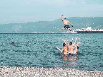 Man jumping on sea against sky