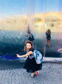 High angle view of smiling girl walking on footpath by glass