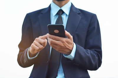 Midsection of man using mobile phone against white background