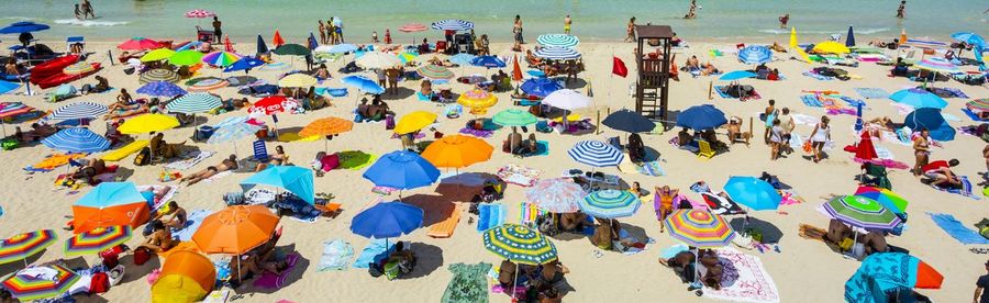 High angle view of people relaxing under parasols at beach