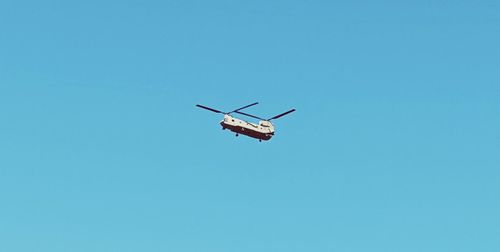 Low angle view of airplane against clear blue sky