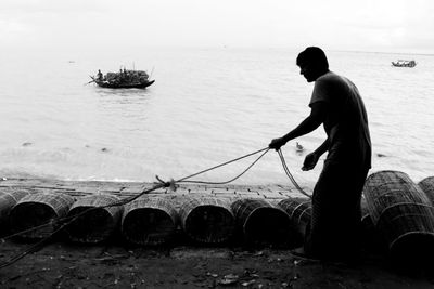 Man fishing in sea against sky