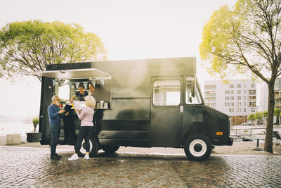 Owners talking to senior customers while standing in commercial land vehicle