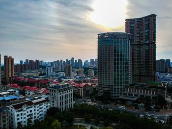 Modern buildings in city against sky during sunset