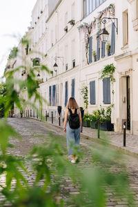 Rear view of woman standing by buildings in city