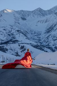 Rear view of woman sitting on snowcapped mountain