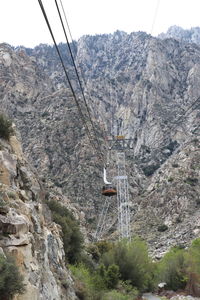 Low angle view of overhead cable car against mountains