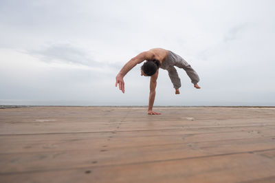 Full length of woman jumping on beach against sky