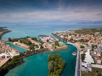 High angle view of city by sea against sky