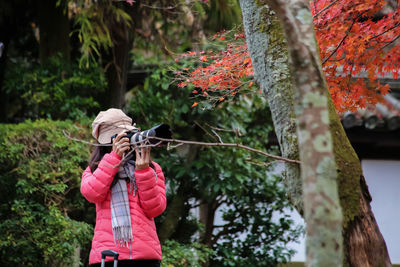 Full length of boy photographing on tree trunk