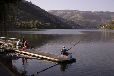 Men fishing in lake against sky