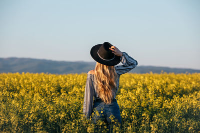 Rear view of woman standing on field against clear sky