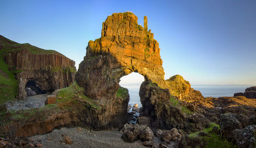 Rock formations in sea against clear sky