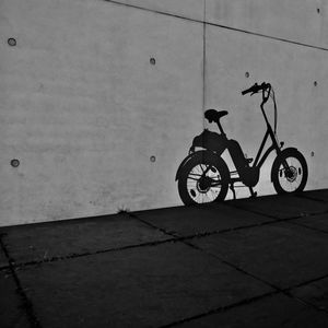 Bicycle parked on footpath by wall