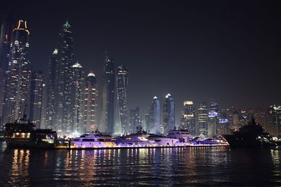 Illuminated buildings by city against sky at night