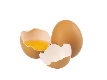 Close-up of broken egg against white background