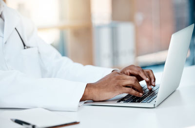 Midsection of doctor using laptop on table