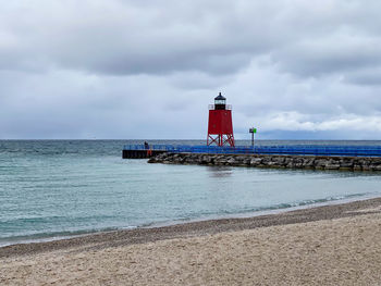 Lighthouse by sea against sky