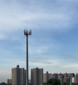 Communications tower in city against sky