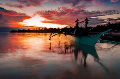 Silhouette boat in lake against sky during sunset