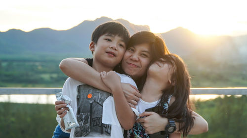 Portrait of happy friends smiling against mountains