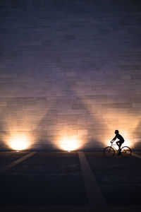 Side view of a silhouette man bicycling on road