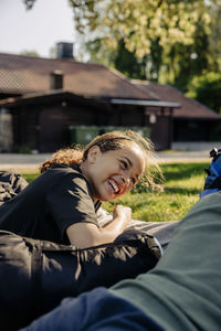 Side view of happy girl laughing while lying down at summer camp