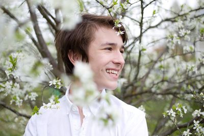 Portrait of young man standing against trees